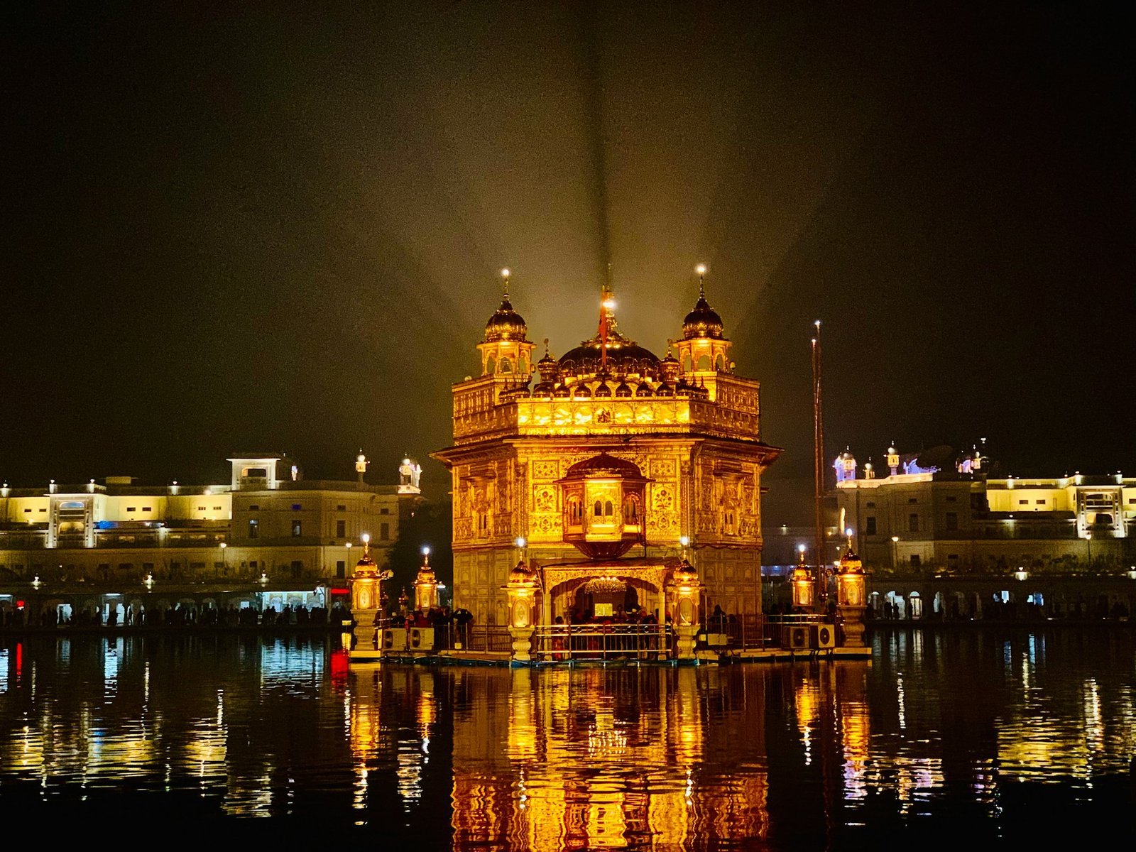 The Golden Temple in Amritsar lit up at night, reflected in the surrounding sacred pool