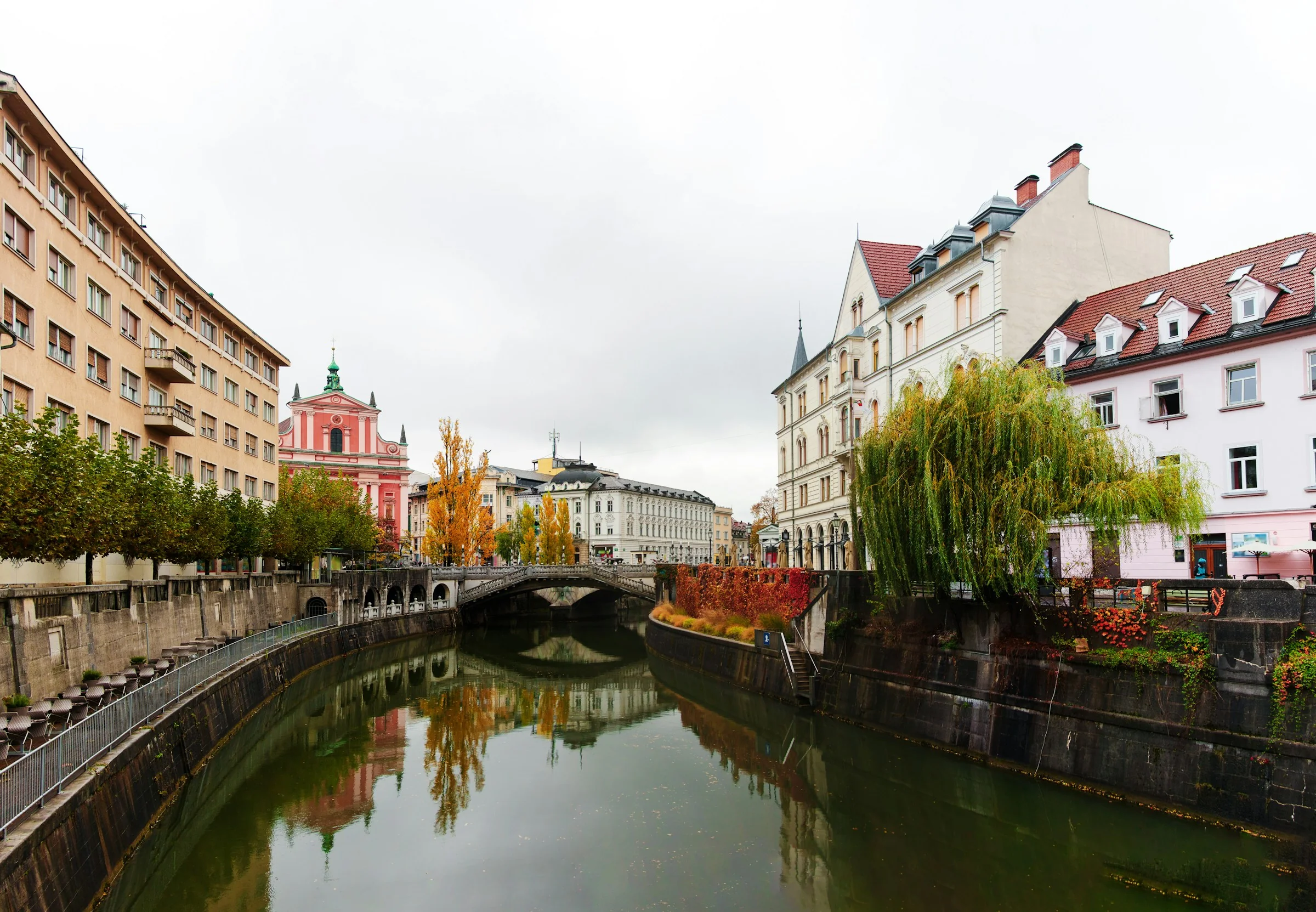 The Ljubljanica river in Ljubljana, Slovenia, with the Triple Bridge and the pink Franciscan Church behind it