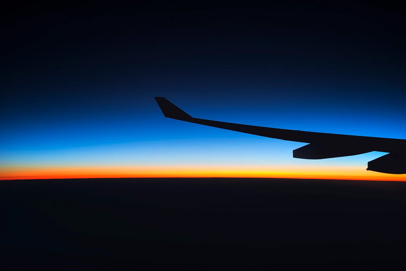 View from an aircraft window at sunrise above the clouds